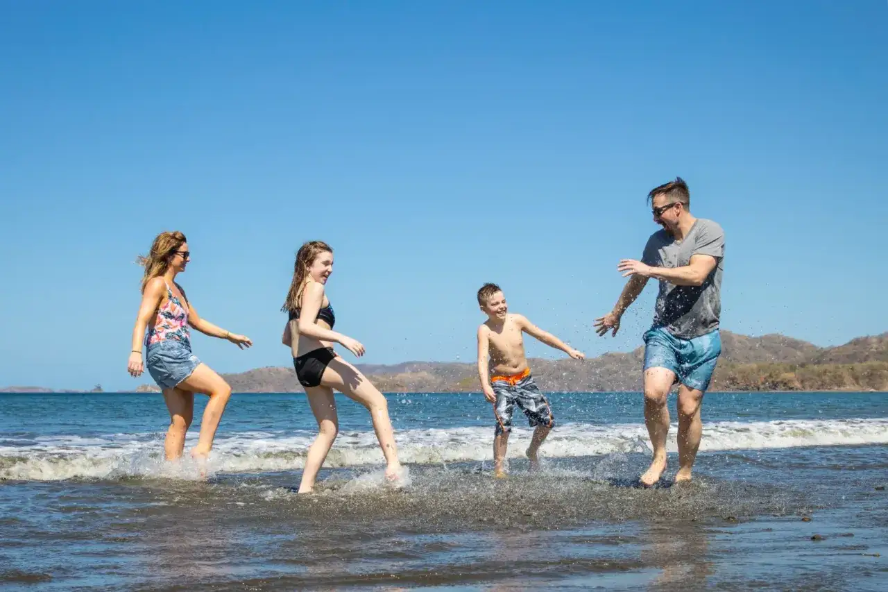 Famiglia felice che gioca nell'acqua del mare, una vacanza indimenticabile in Costa Rica con bambini.
