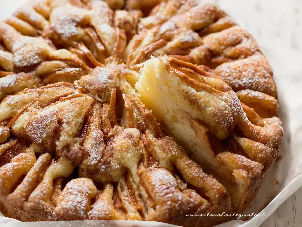 Una deliziosa torta di mele, con fette di mela disposte a raggiera e spolverata di zucchero a velo.