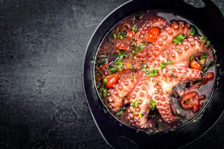 Polpo alla luciana in padella, con pomodorini e prezzemolo. Un piatto succulento e profumato, pronto per essere gustato.