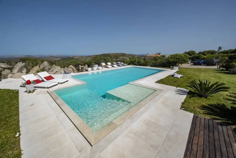 Lussuosa piscina in Sardegna, con vista mare e colline. Ideale per rilassarsi dopo un viaggio in traghetto.